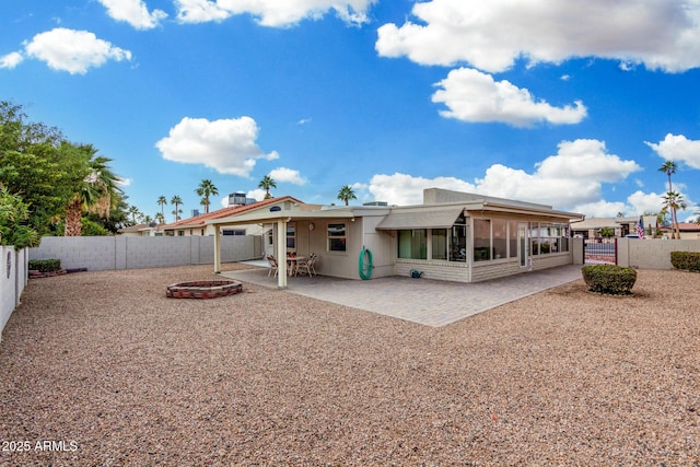 rear view of property featuring a sunroom, a fire pit, and a patio area