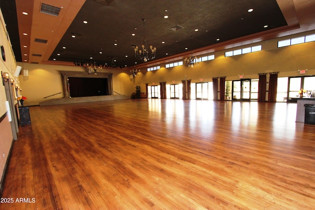 interior space featuring a notable chandelier, light hardwood / wood-style floors, and a raised ceiling