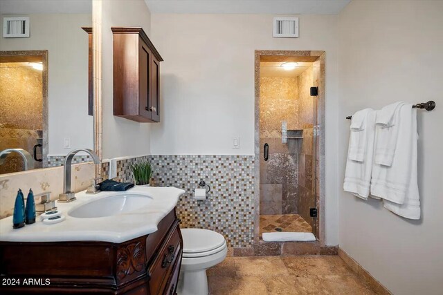 bathroom with vanity, a shower with shower door, tile walls, and toilet