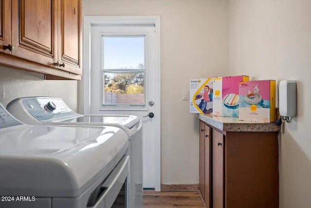 clothes washing area with cabinets, light wood-type flooring, and washer and clothes dryer