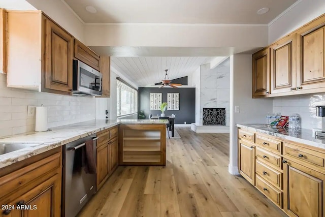 kitchen featuring vaulted ceiling, appliances with stainless steel finishes, kitchen peninsula, backsplash, and light wood-type flooring