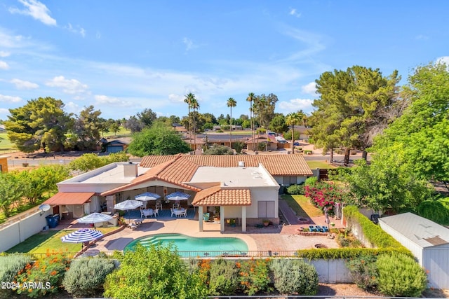 rear view of property featuring a fenced in pool, a patio, a fenced backyard, a tiled roof, and stucco siding