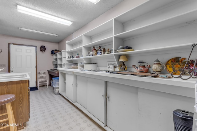 interior space featuring light tile patterned floors, a textured ceiling, and sink