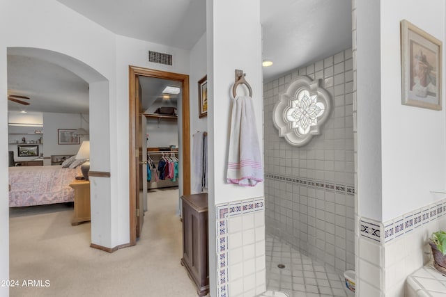 bathroom with tiled shower and ceiling fan