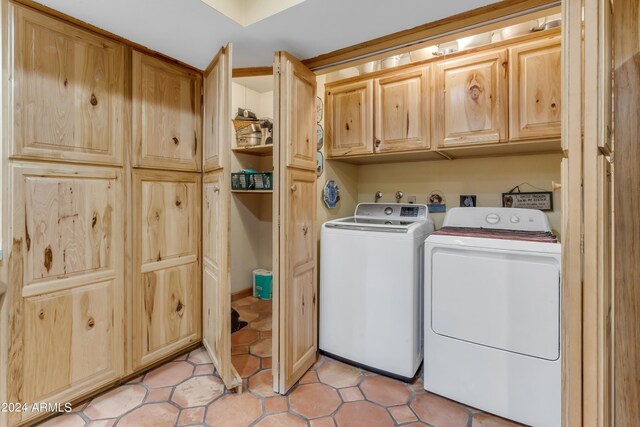 laundry room featuring light tile patterned floors, cabinets, and washer and dryer