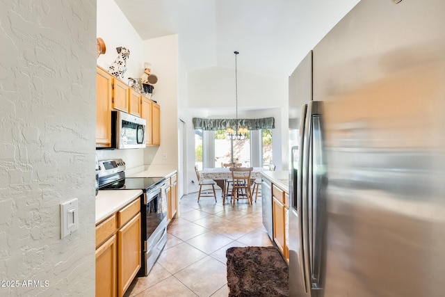 kitchen with light tile patterned floors, hanging light fixtures, stainless steel appliances, vaulted ceiling, and a chandelier