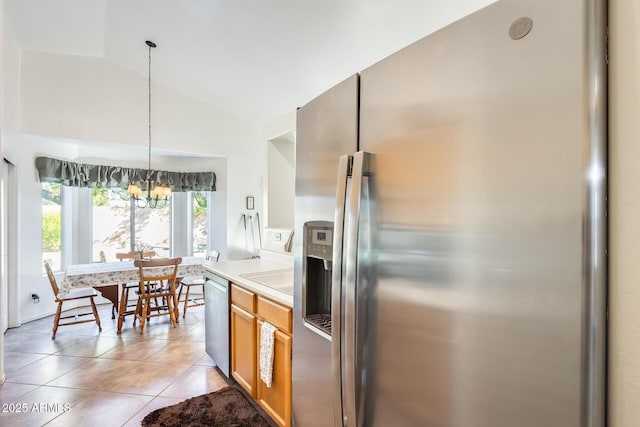 kitchen featuring light tile patterned flooring, appliances with stainless steel finishes, pendant lighting, lofted ceiling, and a chandelier