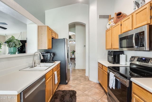 kitchen with appliances with stainless steel finishes, sink, light tile patterned floors, and light brown cabinets