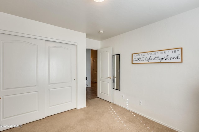 unfurnished bedroom with light carpet and a closet