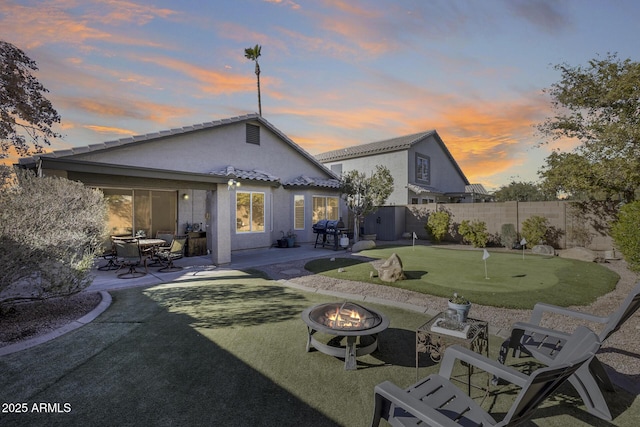 back house at dusk with a patio area and an outdoor fire pit