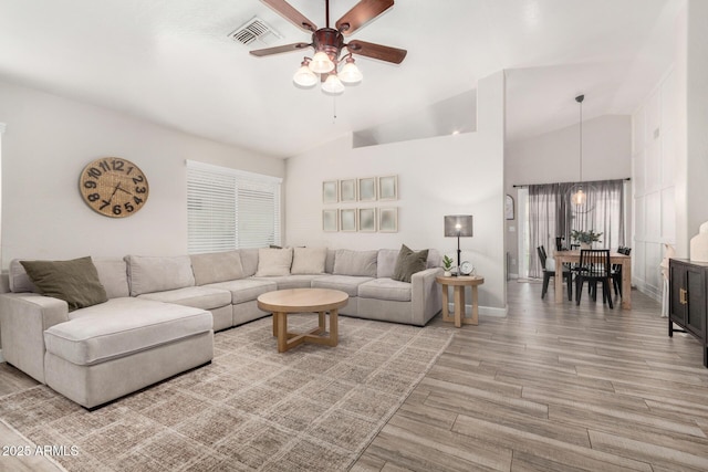 living room with visible vents, light wood-style flooring, a ceiling fan, high vaulted ceiling, and baseboards