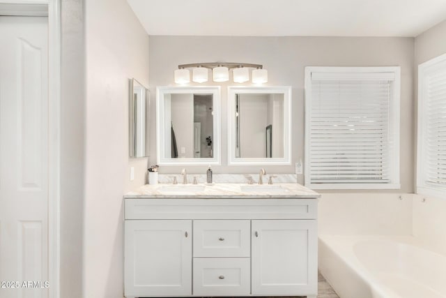 full bathroom featuring double vanity, a garden tub, and a sink