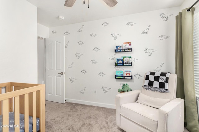 carpeted bedroom with a nursery area, ceiling fan, and baseboards