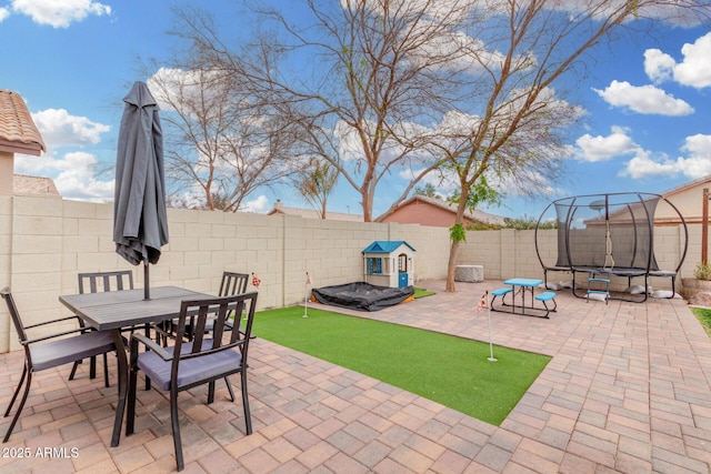 view of patio / terrace featuring a fenced backyard, a trampoline, and outdoor dining space