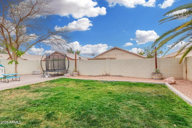 view of yard featuring a trampoline, a patio area, and a fenced backyard