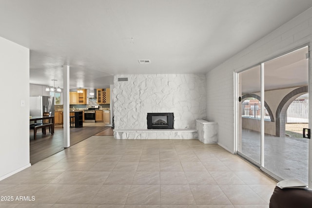 5802 N 61st Dr, Glendale, AZ 85301 - unfurnished living room with a stone fireplace, light tile patterned floors, and a chandelier