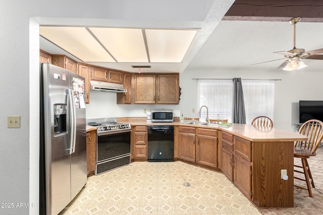 kitchen featuring a breakfast bar area, under cabinet range hood, a peninsula, light countertops, and appliances with stainless steel finishes