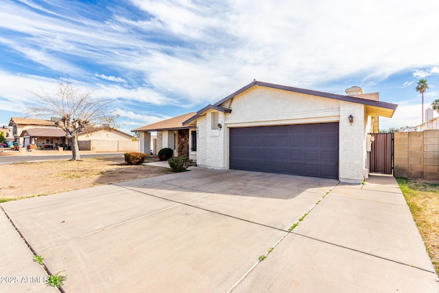 view of front facade featuring a garage, driveway, fence, and stucco siding