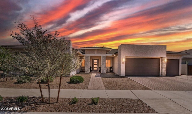 view of front of house featuring an attached garage, decorative driveway, and stucco siding