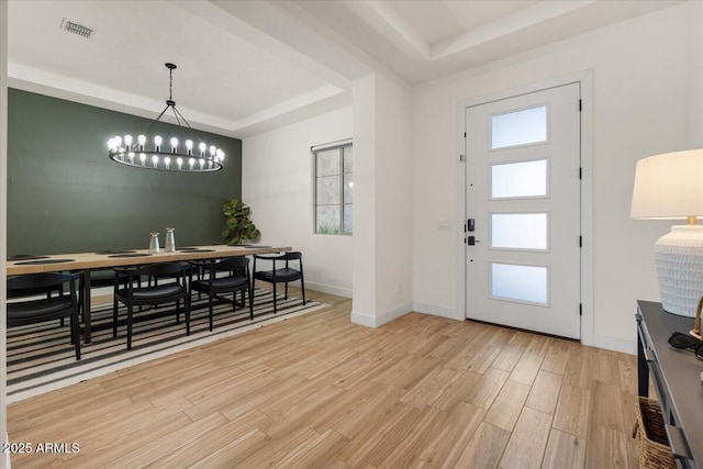 entrance foyer with visible vents, a raised ceiling, a wealth of natural light, and light wood-style floors