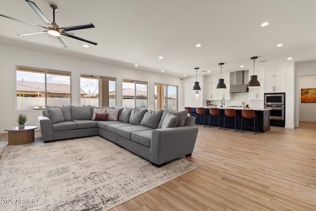 living room with recessed lighting, a ceiling fan, and light wood-style floors