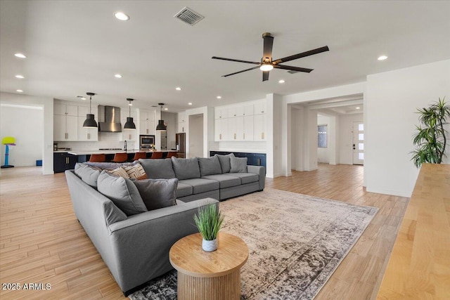 living area featuring a ceiling fan, visible vents, baseboards, recessed lighting, and light wood-style flooring