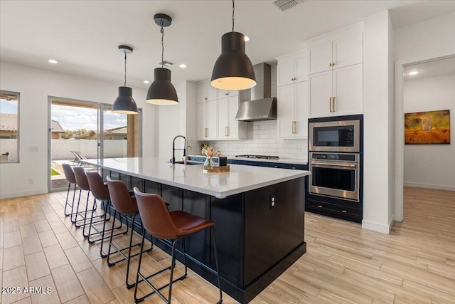 kitchen with a sink, wall chimney exhaust hood, stainless steel appliances, baseboards, and backsplash