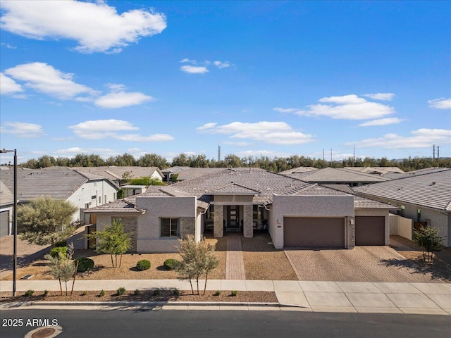 view of front of home featuring a garage, stucco siding, a tiled roof, driveway, and a residential view