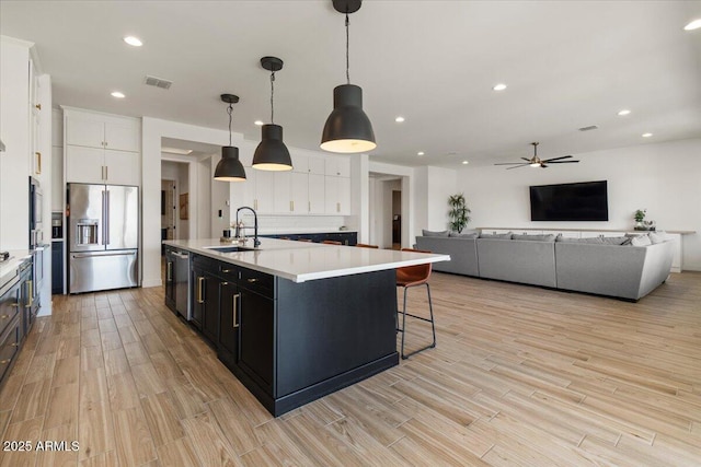 kitchen featuring visible vents, appliances with stainless steel finishes, a sink, light wood finished floors, and white cabinetry