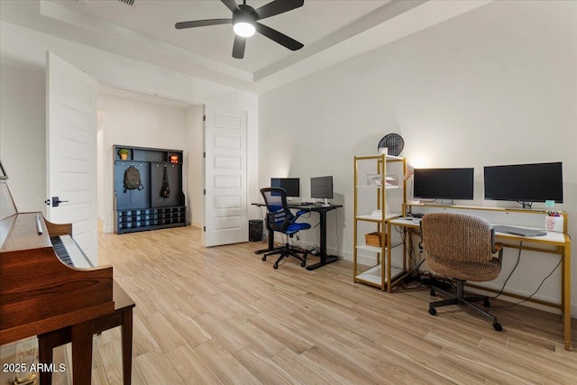 home office with a tray ceiling, baseboards, a ceiling fan, and wood finished floors
