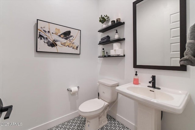 half bath featuring toilet, baseboards, and tile patterned flooring