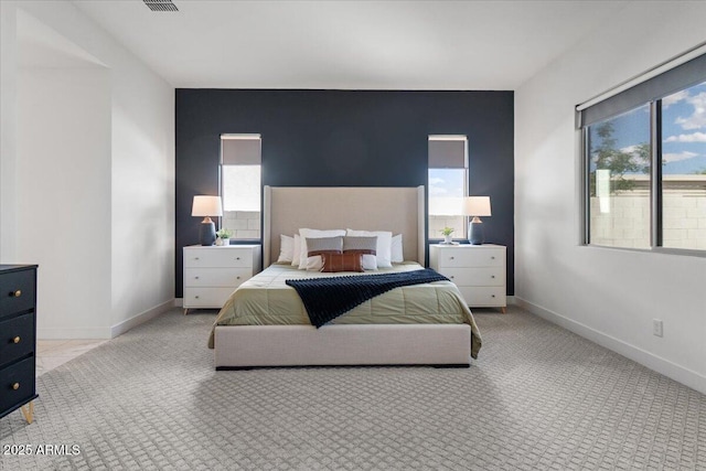 carpeted bedroom with baseboards, multiple windows, and an accent wall