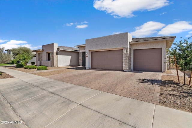 view of front of home with decorative driveway, an attached garage, and stucco siding