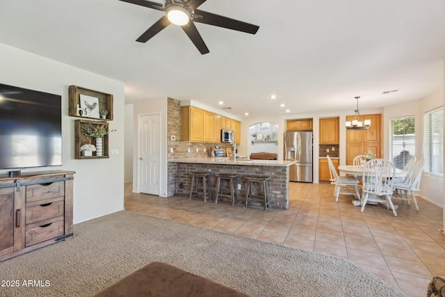 kitchen with stainless steel appliances, a peninsula, light tile patterned flooring, and decorative backsplash