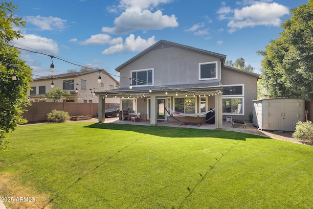 rear view of house with an outbuilding, fence, a shed, stucco siding, and a patio area