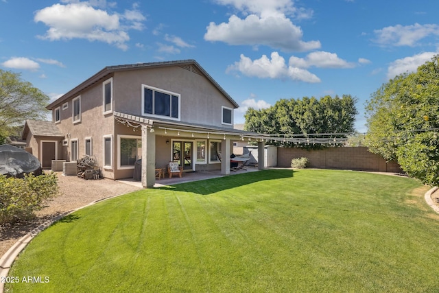 back of property with a patio, a yard, fence, and stucco siding