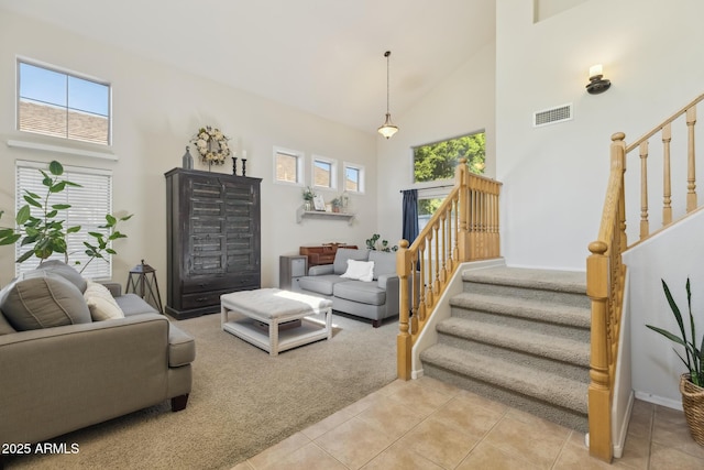 living area featuring visible vents, stairway, and high vaulted ceiling