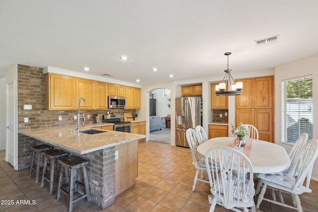 kitchen featuring tasteful backsplash, visible vents, arched walkways, stainless steel appliances, and a sink