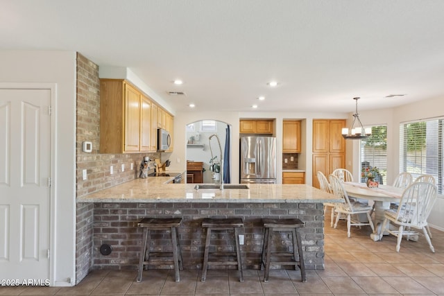 kitchen featuring a peninsula, light stone counters, tasteful backsplash, and appliances with stainless steel finishes