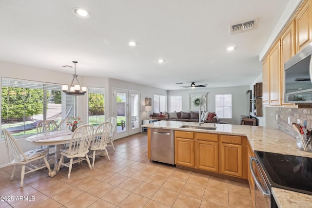 kitchen featuring visible vents, decorative backsplash, appliances with stainless steel finishes, a peninsula, and a sink