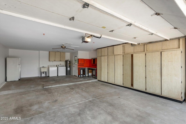 garage featuring washer and dryer, water heater, white refrigerator, a garage door opener, and ceiling fan