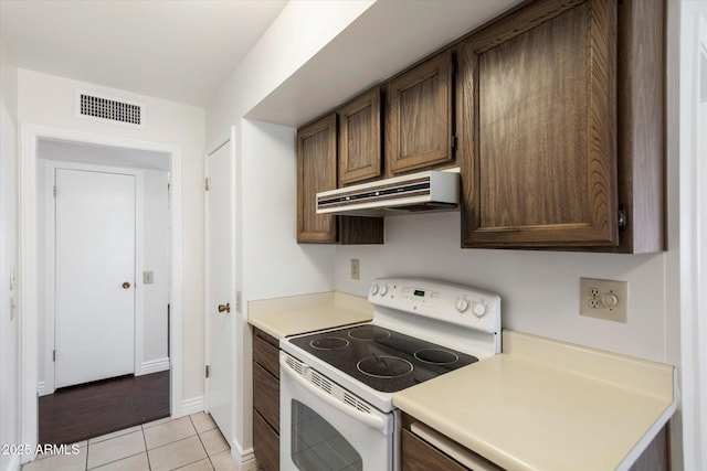 kitchen with light tile patterned flooring, white electric range, and dark brown cabinetry