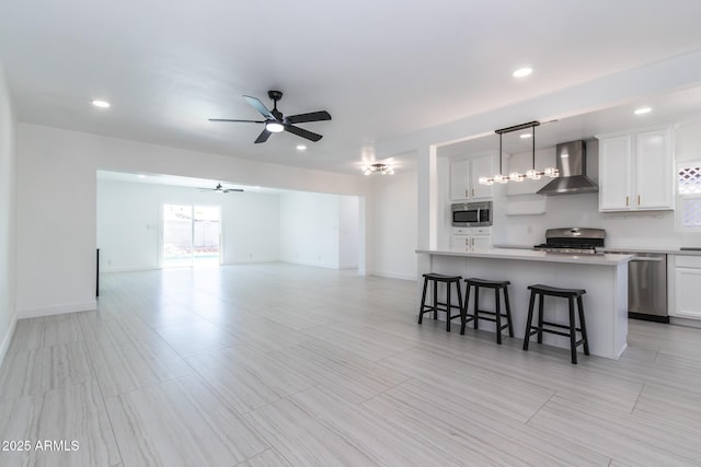 1011 W Weldon Ave, Phoenix, AZ 85013 - kitchen with wall chimney range hood, stainless steel appliances, a ceiling fan, a breakfast bar area, and open floor plan