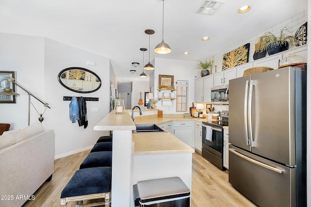 948 E Savannah Dr, Chandler, AZ 85225 - kitchen featuring appliances with stainless steel finishes, a peninsula, a kitchen breakfast bar, light countertops, and a sink