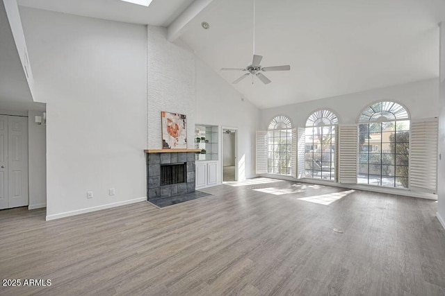 unfurnished living room with a tiled fireplace, high vaulted ceiling, light hardwood / wood-style flooring, and a wealth of natural light