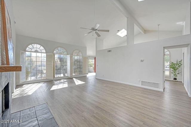 unfurnished living room featuring ceiling fan, beam ceiling, high vaulted ceiling, a fireplace, and light wood-type flooring