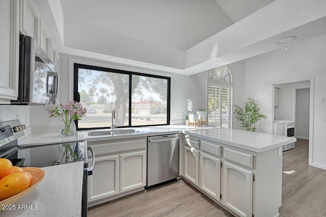 kitchen with white cabinetry, sink, kitchen peninsula, and appliances with stainless steel finishes