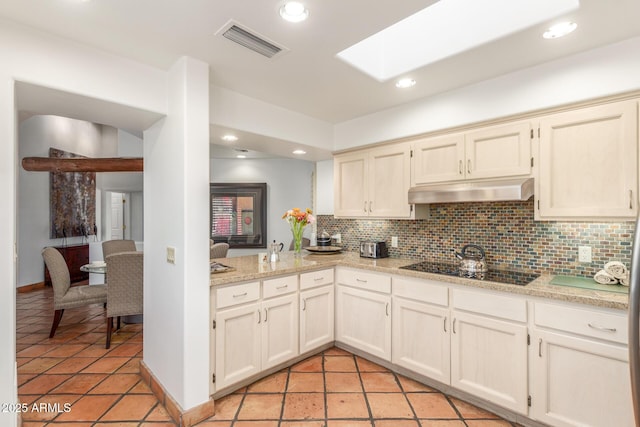 kitchen with black electric stovetop, decorative backsplash, a skylight, and cream cabinetry