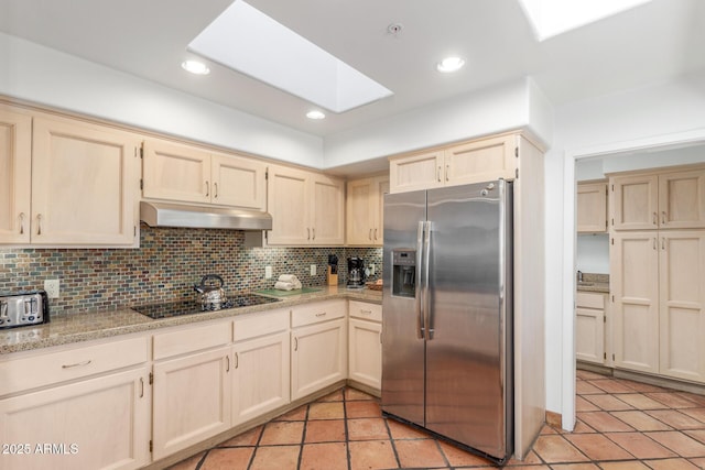 kitchen with black electric stovetop, a skylight, stainless steel fridge with ice dispenser, and decorative backsplash