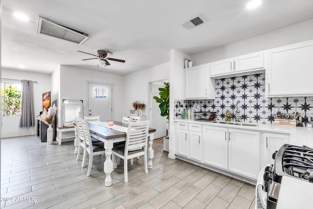 kitchen featuring white cabinetry, sink, tasteful backsplash, and stainless steel gas range oven